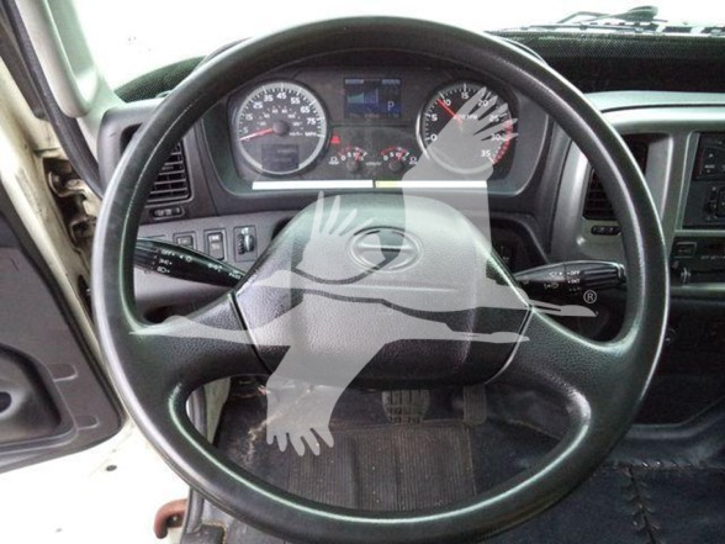 Dashboard and steering wheel view of a 2015 Hino 268a refrigerated truck interior showing steering wheel and instrument cluster.