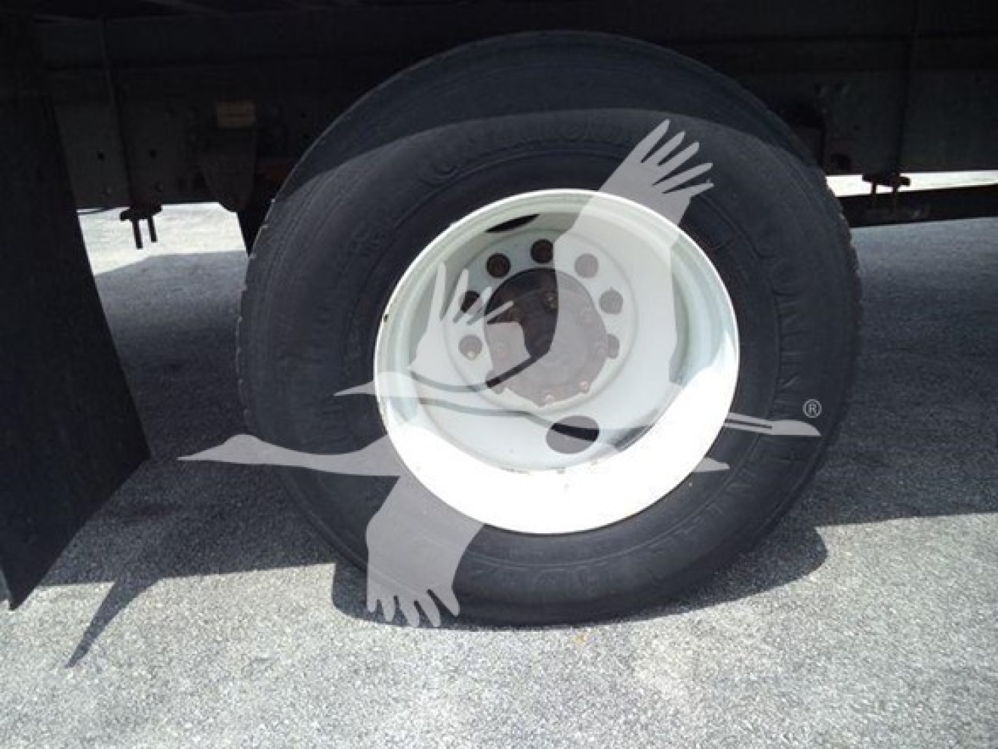 Wheel and tire of a 2015 Hino 268a refrigerated truck showing a white steel wheel and tire under a trailer.