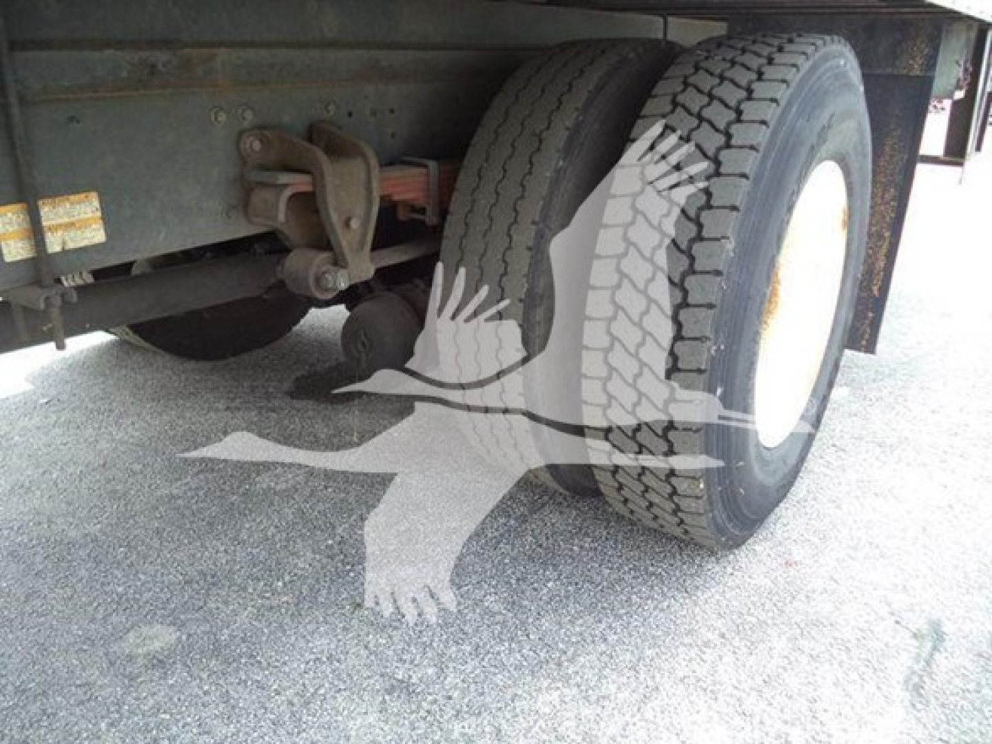 Truck rear axle and dual rear tires of a refrigerated 2015 Hino 268a showing wheel and suspension components.