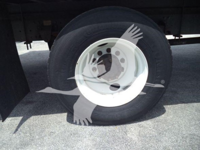 Wheel and tire of a 2015 Hino 268a refrigerated truck showing a white steel wheel and tire under a trailer.