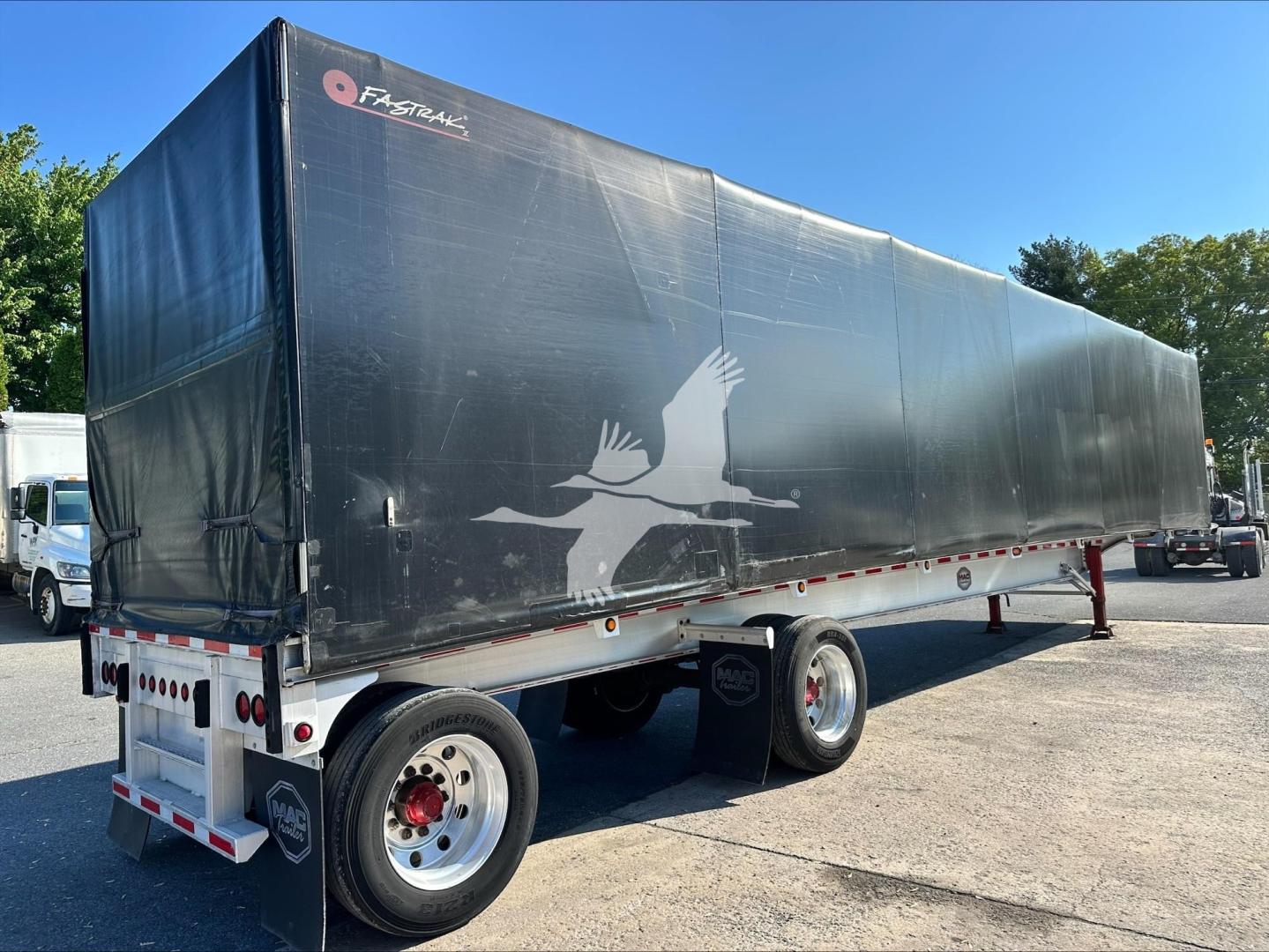 Trailer side with curtain sides showing a white silhouette graphic and FastTrac branding on black tarpaulin.