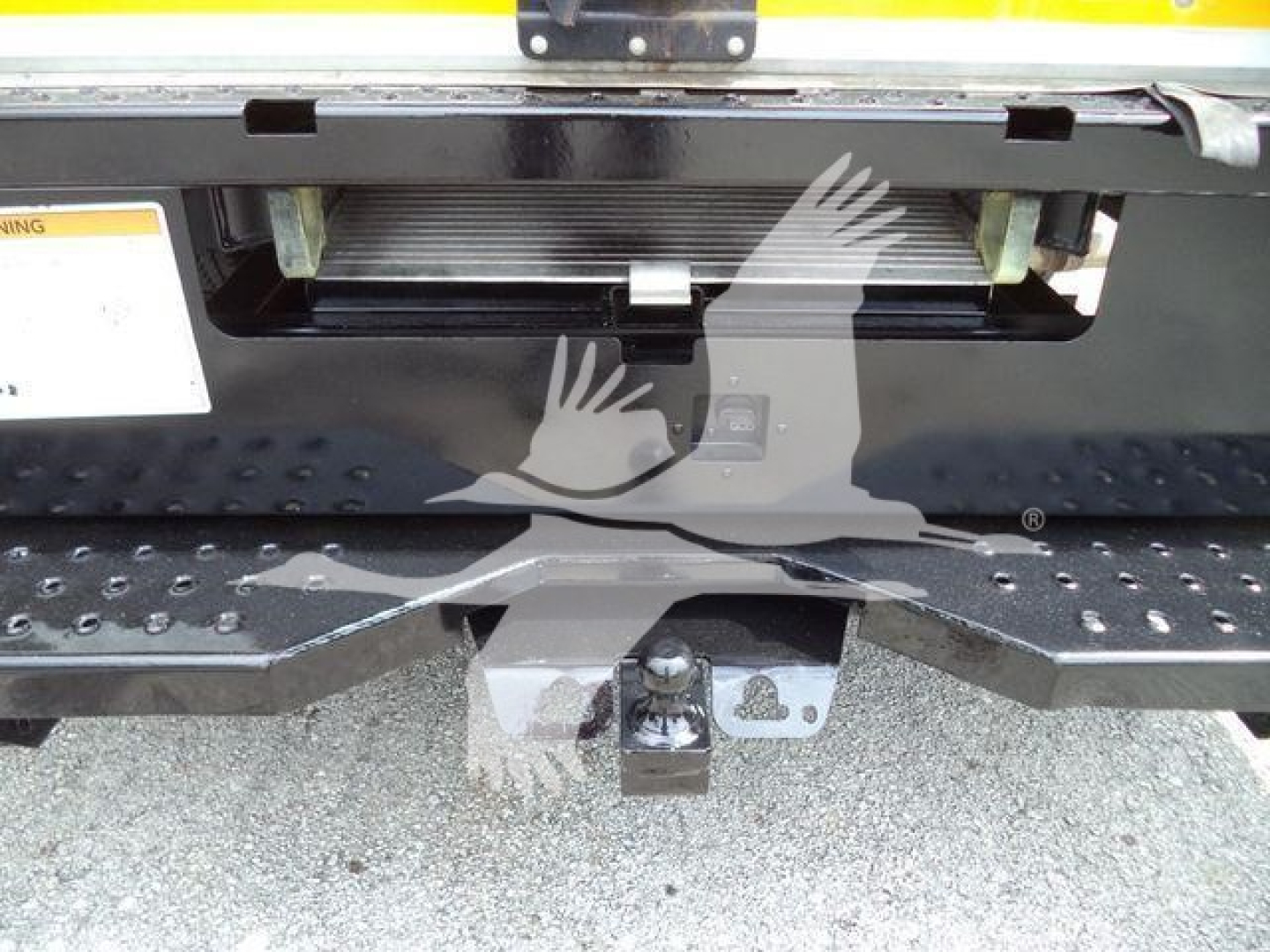 Ford E-350 XL SD rear view showing hitch and step bumper with black spare area.