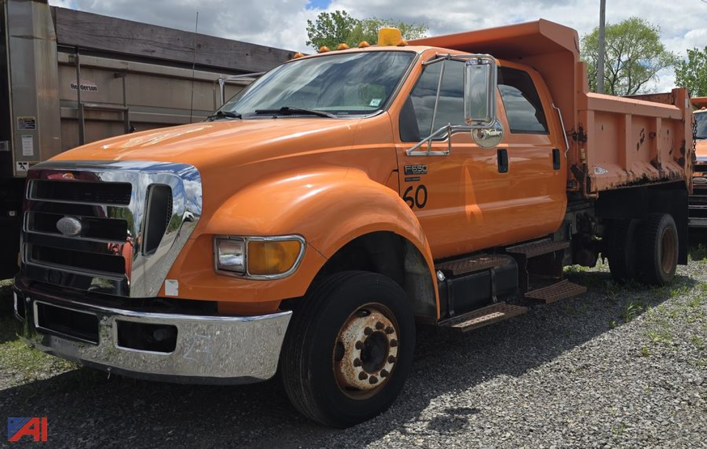 Orange Ford F-650 dump truck side view showing dump bed and chrome front bumper