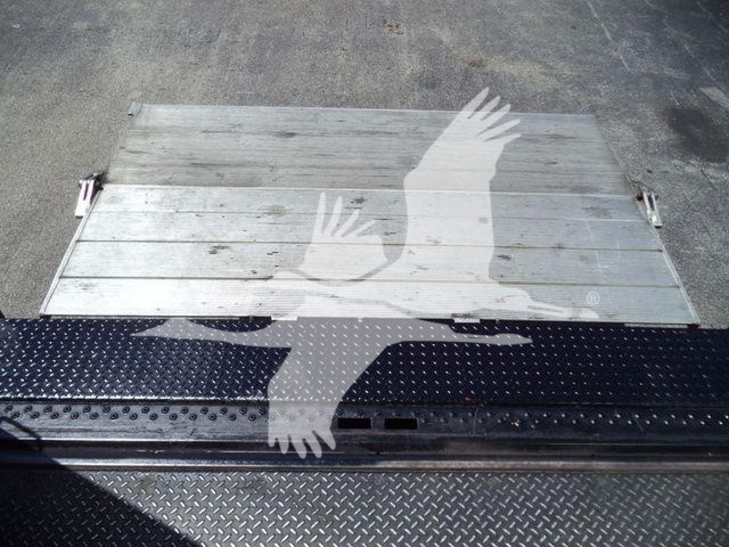 Isuzu NPR HD truck bed or tailgate panel with metal step, visible serial/foil textures, no readable text.