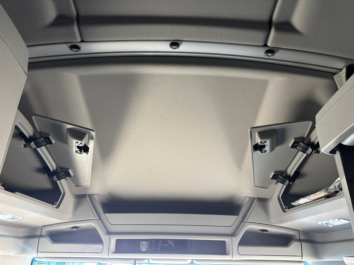 Cab interior of a 2024 Kenworth T680 sleeper truck showing overhead panel and vanity/storage compartments.