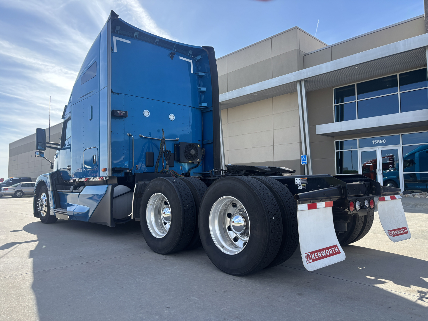 Kenworth T680 side-rear view with blue cab and dual rear axles, tandem setup, white mudflaps labeled Kenworth, stock number 0632243 visible near cab, VIN 1XKYD49X0RJ348696 not visible on image.