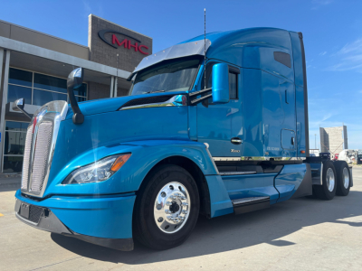 Blue 2024 Kenworth T680 tractor parked outdoors showing front and side view with sleeper cab and chrome wheels.