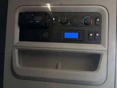Kenworth T680 interior dashboard panel showing control knobs, blue digital display, and storage pocket