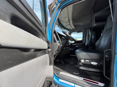 Kenworth T680 truck interior with blue cab; view of driver's seat, dashboard, and open door sill showing interior features.