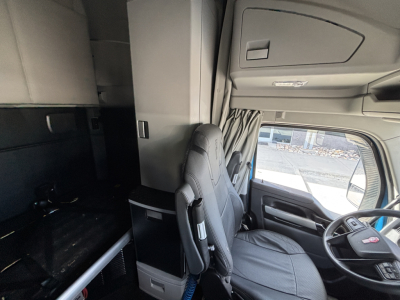 Kenworth T680 sleeper cab interior showing driver seat and dashboard with storage compartments