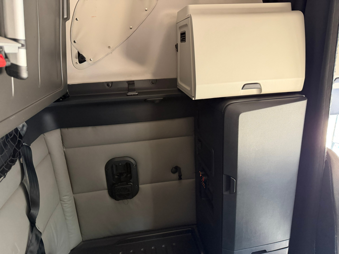 Truck cab interior with sleeper and storage unit; visible text includes no legible labels, only structural components.