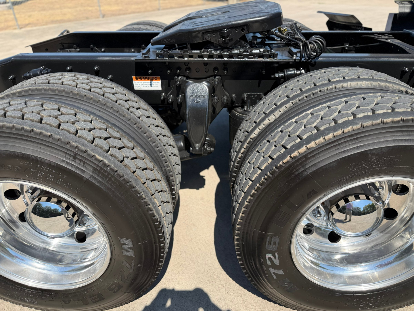 Truck chassis with dual rear axles and dual tires, Freightliner PT126064ST, showing rear suspension and drive axles, no visible text other than tire markings.
