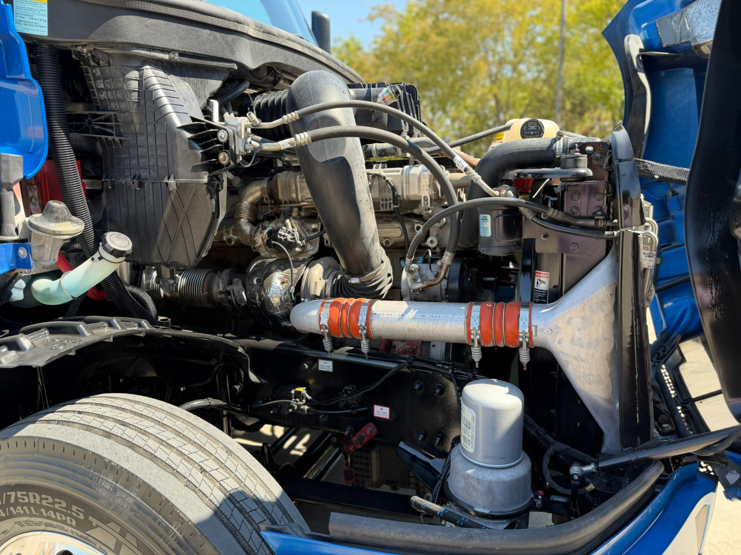 Truck engine bay of a Freightliner PT126064ST showing intake, hoses, and fluid reservoirs with visible engine components.