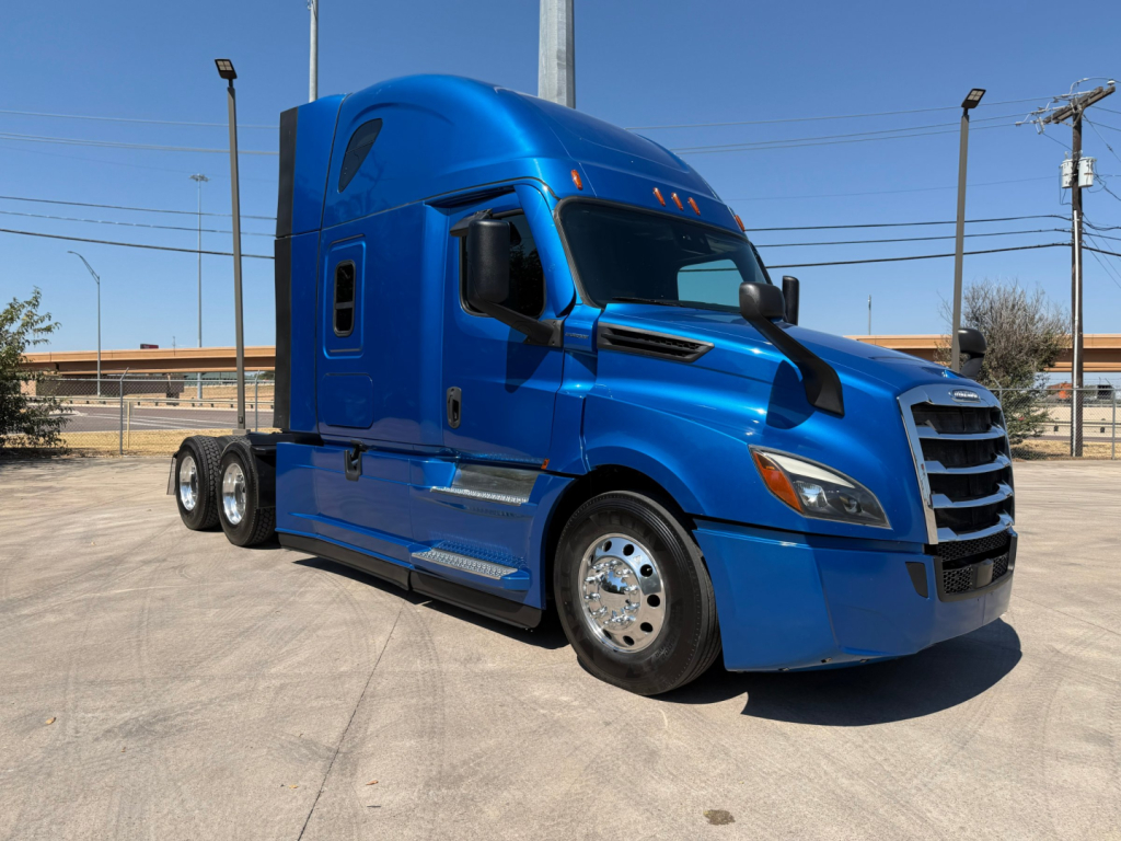 Blue Freightliner PT126064ST sleeper cab tractor showing side view with front grille and wheels.