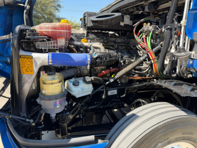 Truck engine bay of a 2022 Freightliner PT126064ST showing coolant reservoir, power steering fluid reservoir, and various colored wiring harnesses.