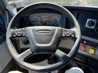 Steering wheel and dashboard of Freightliner PT126064ST truck interior showing steering wheel with Freightliner emblem and instrument cluster