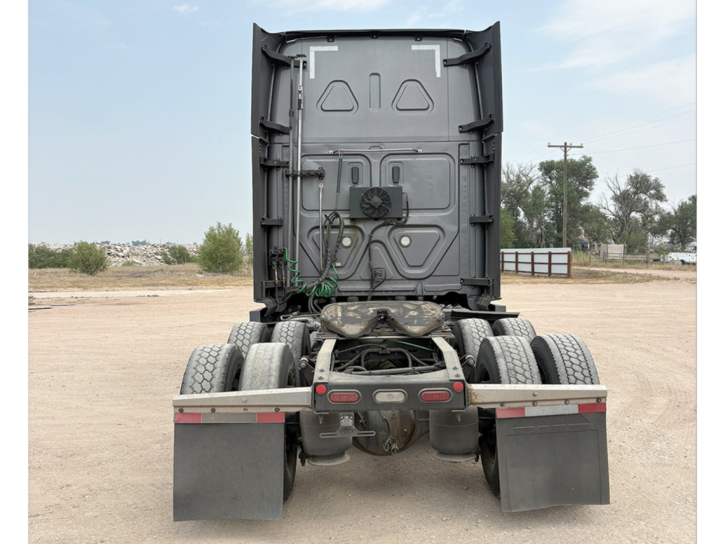 Rear view of a Freightliner Cascadia tractor chassis showing rear power unit clearance, dual rear axles with dual tires, and mud flaps.