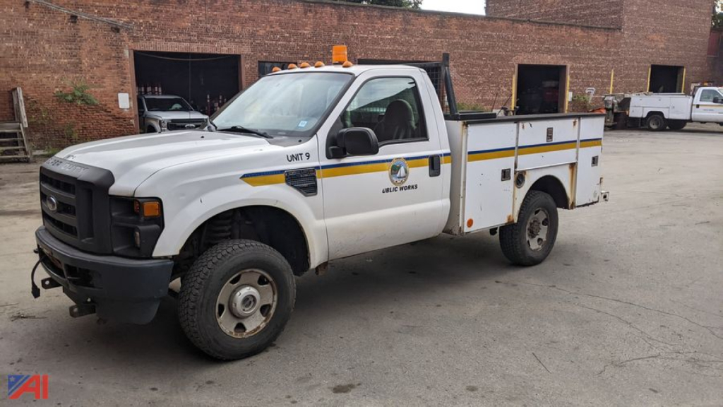 Ford F-350 Super Duty utility truck with plow, white, utility bed with compartments, amber rooftop beacon, front bumper and grille, UNIT 9 on door