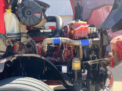 Mack Anthem engine bay with visible coolant reservoir, hoses, and air intake; various fluid reservoirs and engine components visible.