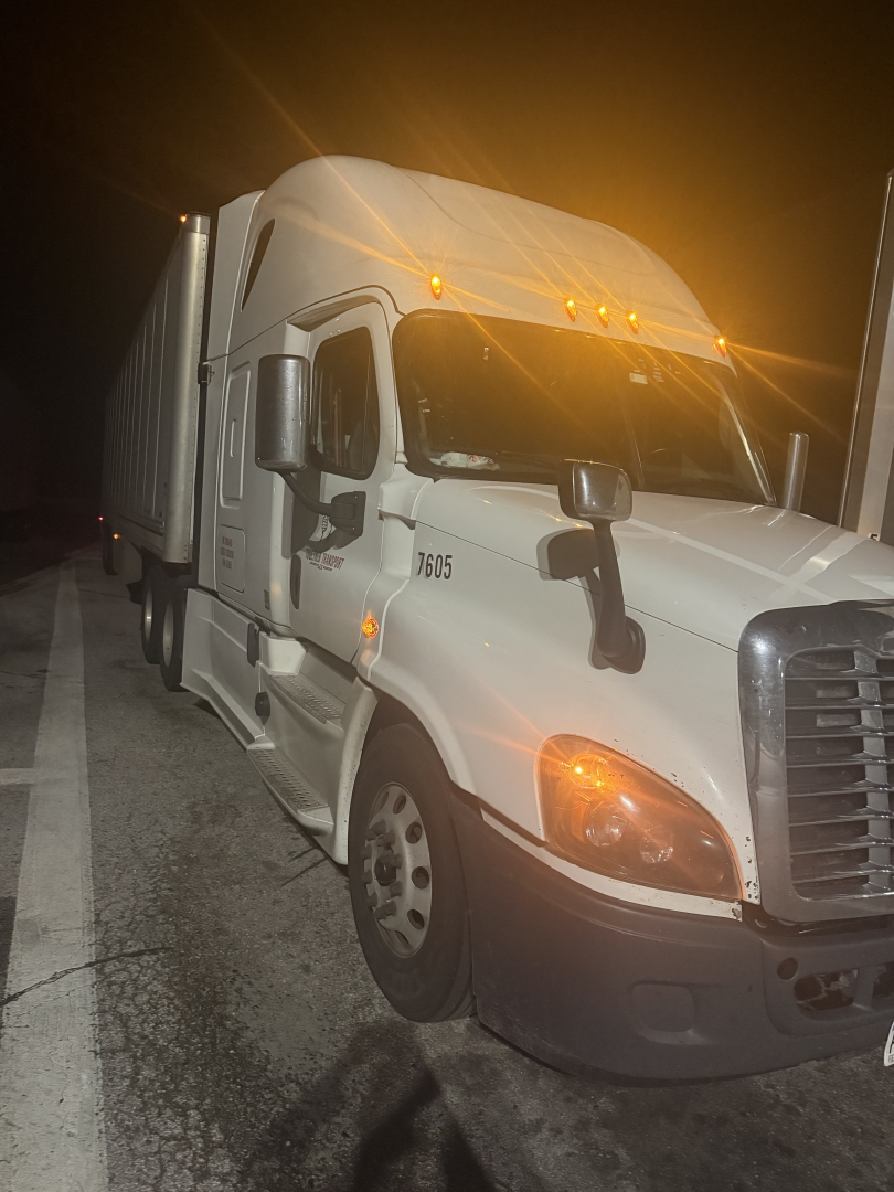 Freightliner Cascadia truck in night shot showing front cab and trailer coupling