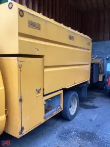Ford F-550 utility dump truck side view showing large yellow dump body with storage compartments and rear wheel, long utility bed.