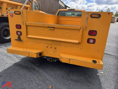 Rear view of a yellow utility dump bed on a Chevrolet Silverado 3500HD chassis, with embossed 'RENTING' on tailgate and taillights visible.