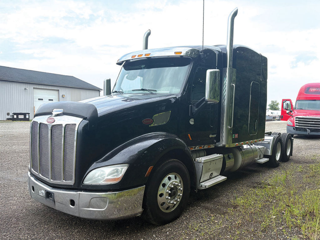 Peterbilt 579 UltraCab tractor in black, side view showing chrome front bumper, grille, tall exhaust stacks, fuel tanks, and aerodynamic sleeper cab.