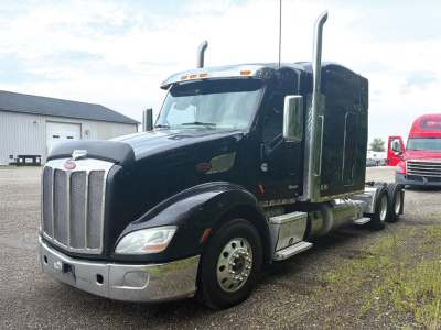 Peterbilt 579 UltraCab tractor in black, side view showing chrome front bumper, grille, tall exhaust stacks, fuel tanks, and aerodynamic sleeper cab.