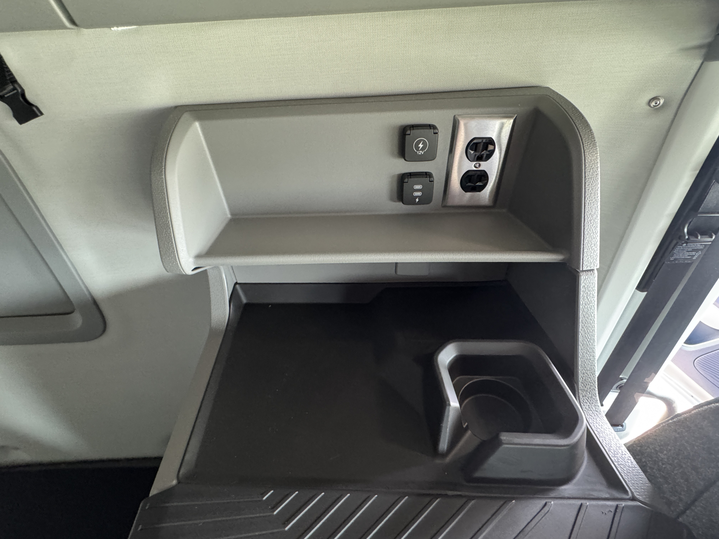 Volvo VNL64T860 cab interior view showing overhead power outlet and small shelf with cup holder in lower dash area.
