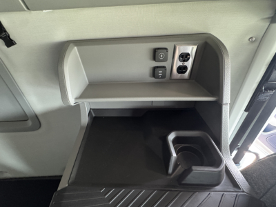 Volvo VNL64T860 cab interior view showing overhead power outlet and small shelf with cup holder in lower dash area.