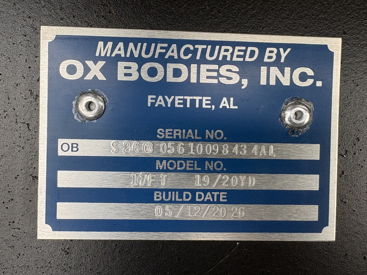 Label plate on a Volvo truck showing Manufactured by Ox Bodies, Inc., Fayette, AL with serial/model numbers and build date.