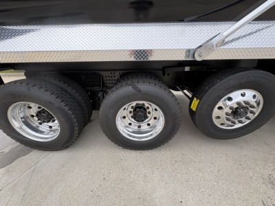 Triple axle of a Volvo dump truck showing three rear wheels and polished rims.