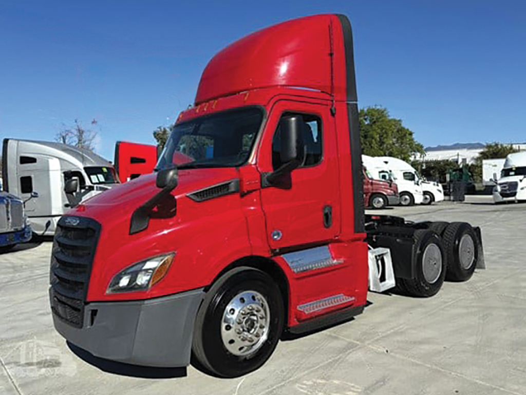 Truck cab side view showing red Freightliner Cascadia tractor with aerodynamic sleeper, front wheel, chrome hubcaps, and black tires.