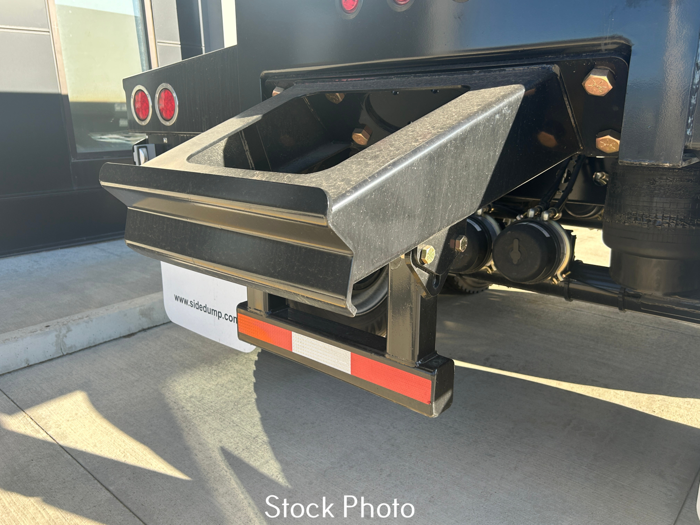 Dump trailer hitch and rear undercarriage with black metal toolbox/steps and red reflective tape, Smithco SX2-4034 trailer component visible.