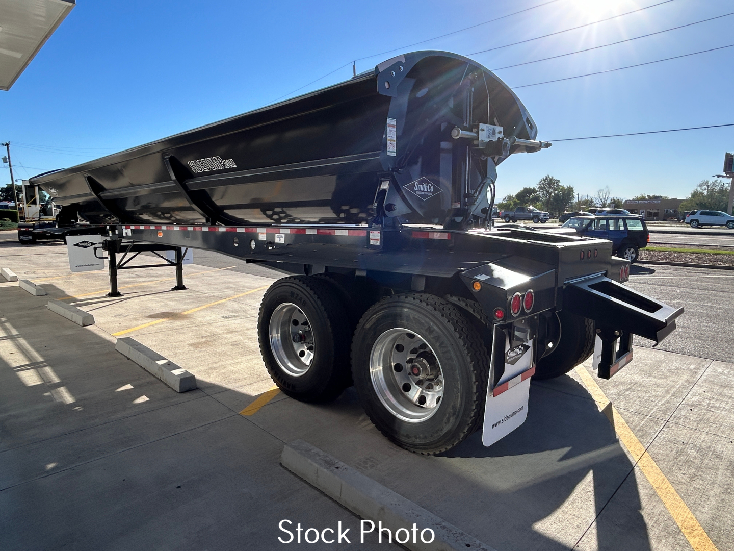 Dump trailer with SX2-4034 model showing dual rear axles and black metal dump body, with branding and decals on side.