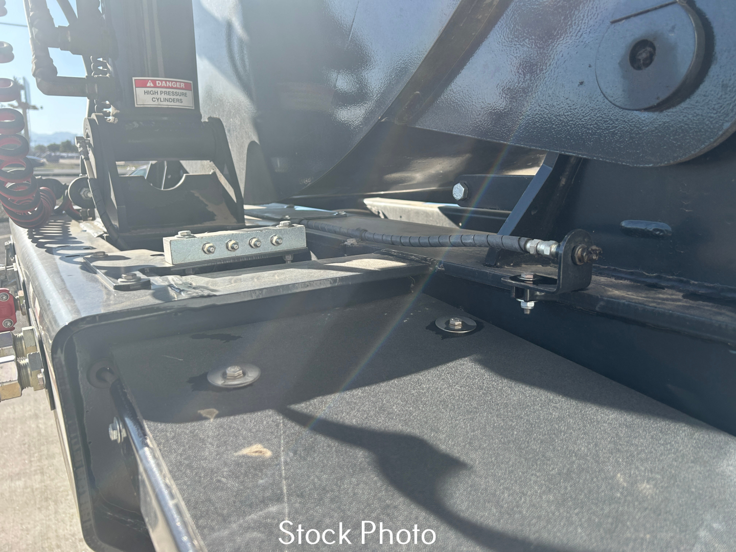 Trailer hitch area of a new Smithco SX2-4034 dump trailer showing hydraulic hose, metal frame, and mounting hardware.