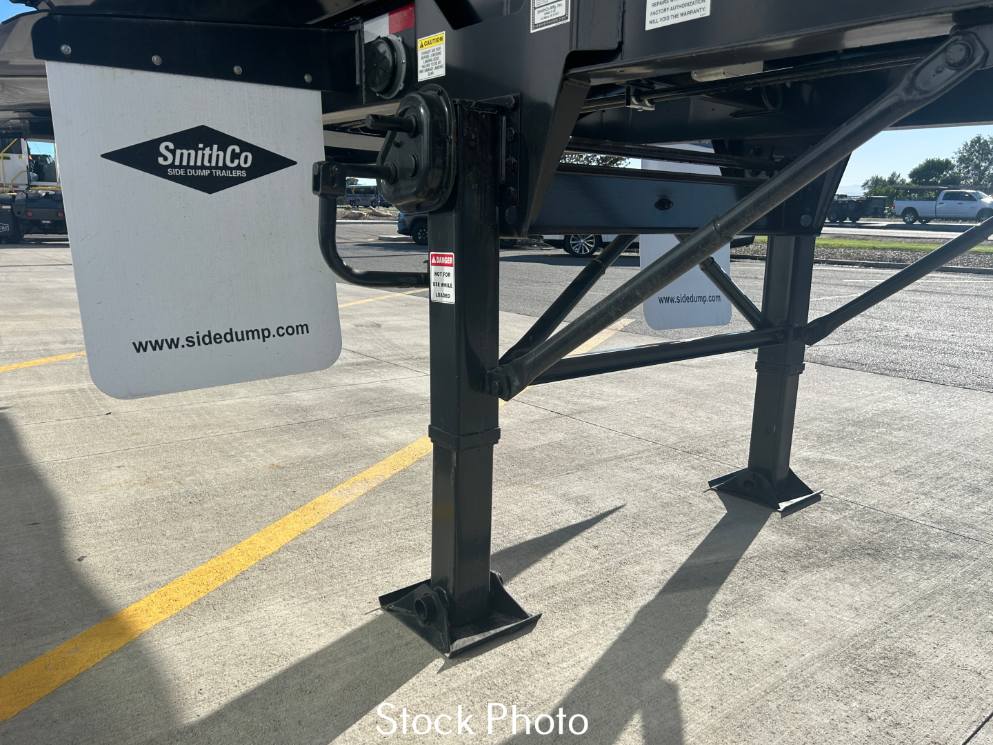 SmithCo SX2-4034 dump trailer landing gear and frame with SmithCo logo on mud flap and website sidetump; tag and support structure visible.