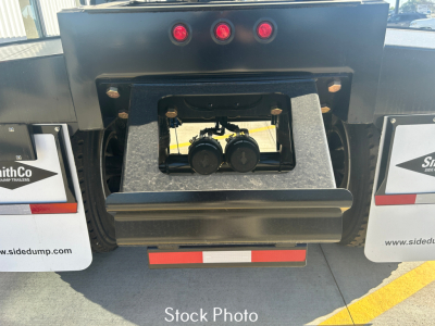 Rear view of a dump trailer showing the hitch area with twin black couplers, three red lights above, and rear bumper with reflective tape; SmithCo branding on mud flaps on both sides.