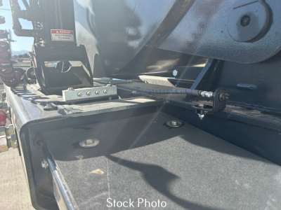 Trailer hitch area of a new Smithco SX2-4034 dump trailer showing hydraulic hose, metal frame, and mounting hardware.