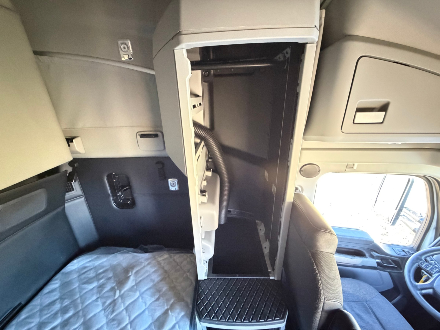 Kenworth T680 sleeper cab interior showing open cabinet/cubby space between driver and passenger seats.