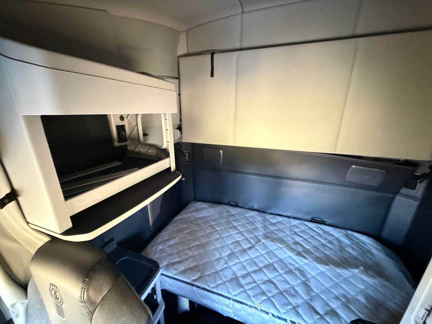 Kenworth T680 sleeper cab interior with bunk bed and storage compartments visible.