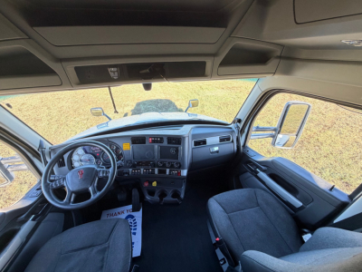 Kenworth T680 interior cab dashboard steering wheel and driver seat with large windshield and side mirrors.