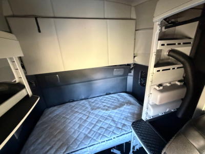 Kenworth T680 sleeper cab interior with bed area and storage cabinets visible.