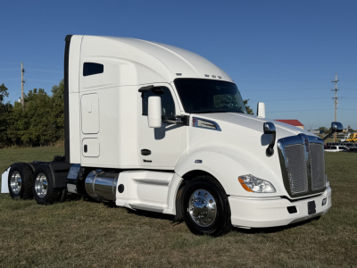 Kenworth T680 tractor in white, side view showing sleeper cab, tandem rear axles, chrome fuel tanks, and grille with 'KENWORTH' badge.