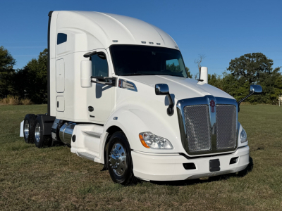 Kenworth T680 conventional sleeper truck with white cab, chrome grille, and dual rear axles; side view showing large mirrors and aerodynamic hood.