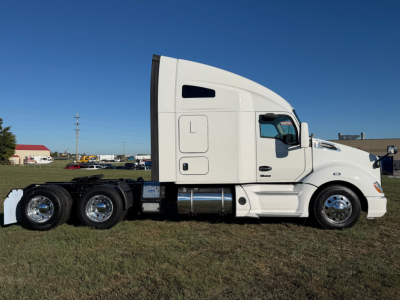 Kenworth T680 sleeper cab truck side view showing white exterior and dual rear axles.
