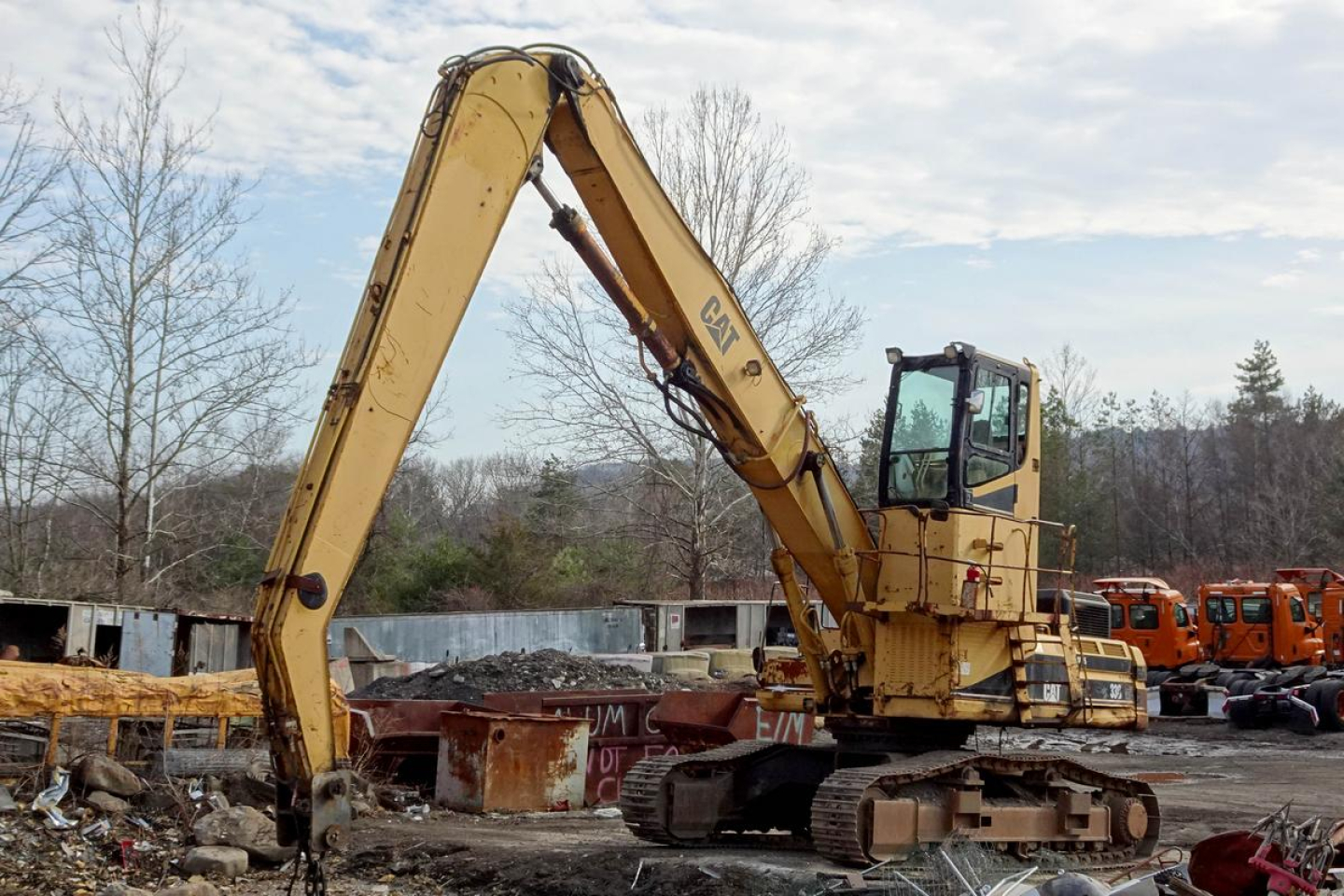 Caterpillar 330L excavator in service bay showing hydraulic arm raised over a work site.