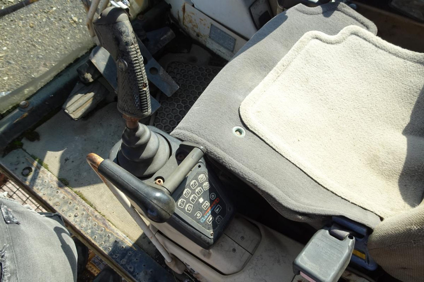Tractor-like control area of a Caterpillar 330L MH with a joystick lever, pedals, and seat; control panel shows numeric keypad and switches.