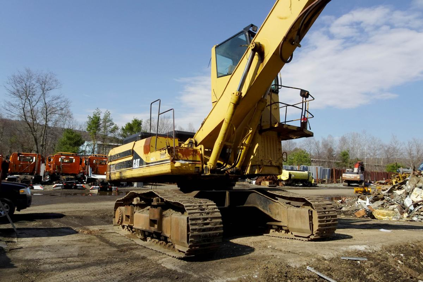 Caterpillar 330L MH excavator in a recycling yard from a side view showing tracked undercarriage and yellow boom with cab.