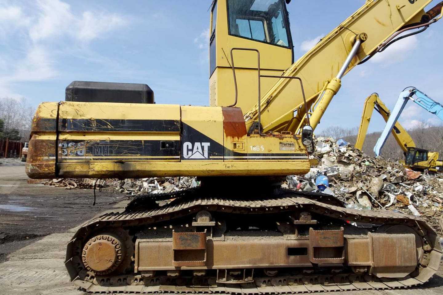 Caterpillar 330L MH tracked excavator in-garage view showing side profile with yellow body and CAT logo on cab and boom.